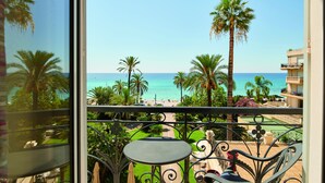 Ein Balkon mit Blick auf den Strand, Palmen und einen Poolbereich.