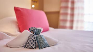 Una cama bien hecha con almohadas y un cojín decorativo con un diseño geométrico.