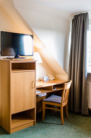 A small room with a desk, chair, television, and a telephone. - Akzent Hotel Zur Grünen Eiche (Bispingen)