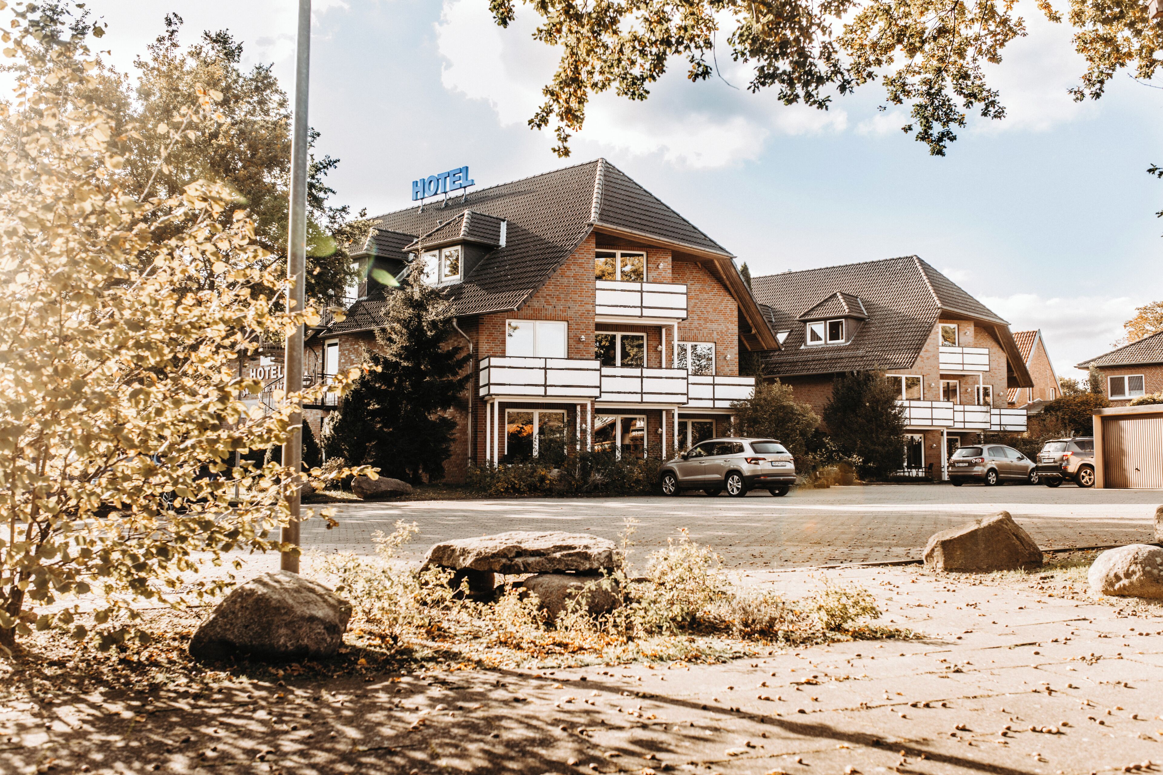 Ein Hotel mit Schilder, vielen Fenstern und einem Parkplatz mit Autos.