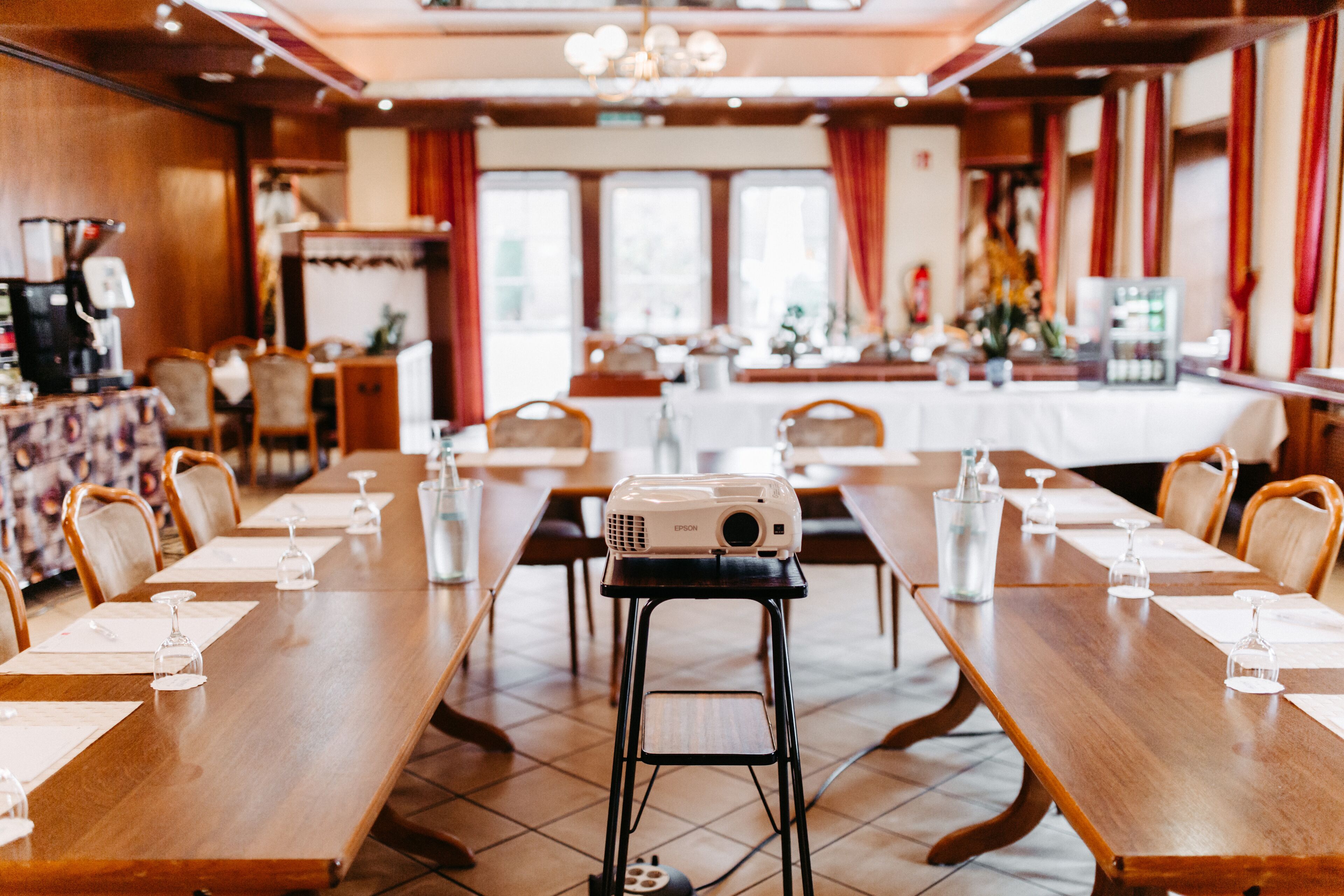 Una sala conferenze con un lungo tavolo, sedie, un proiettore e una macchina del caffè.