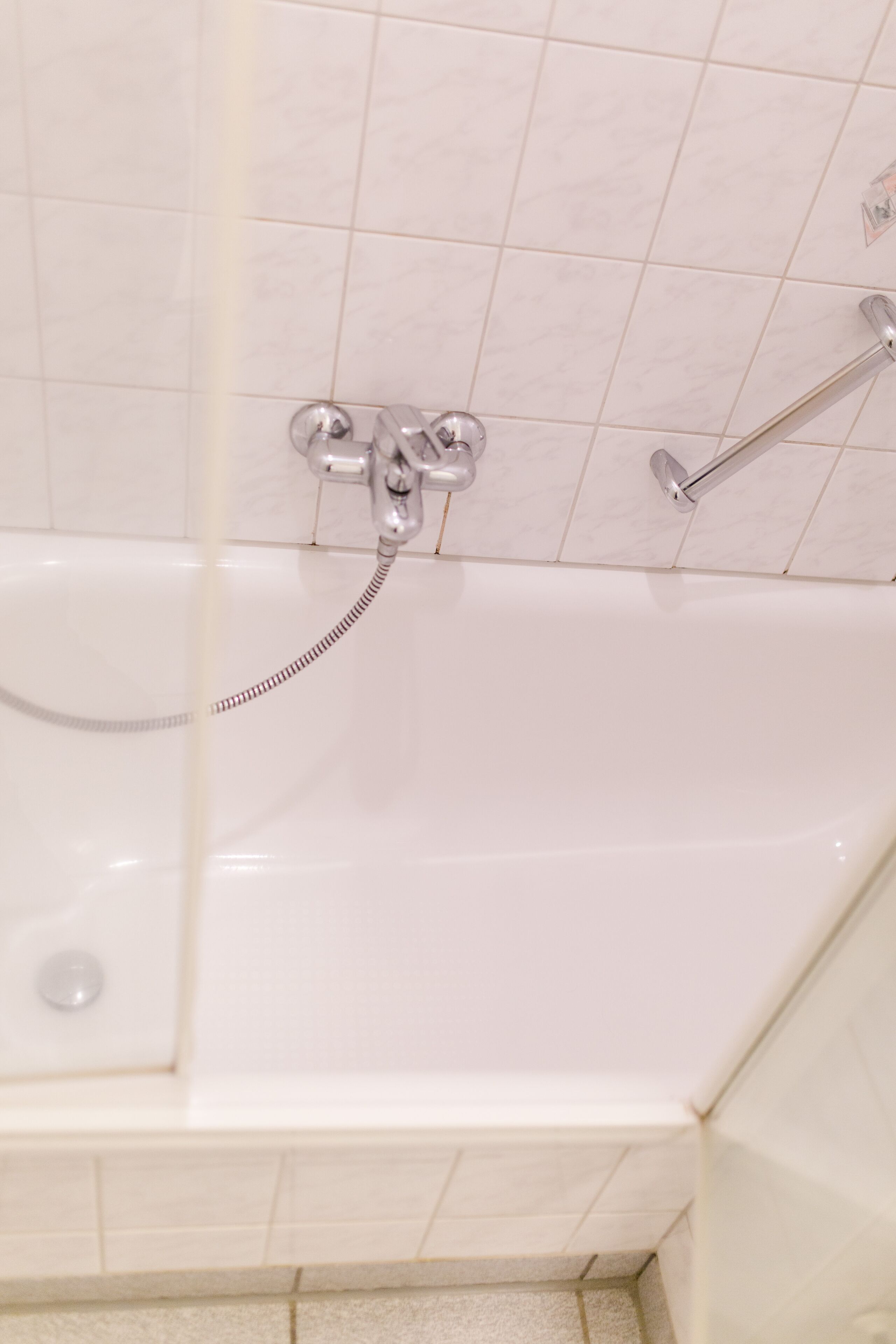 A bathroom with a bathtub, a shower, and a hand shower.