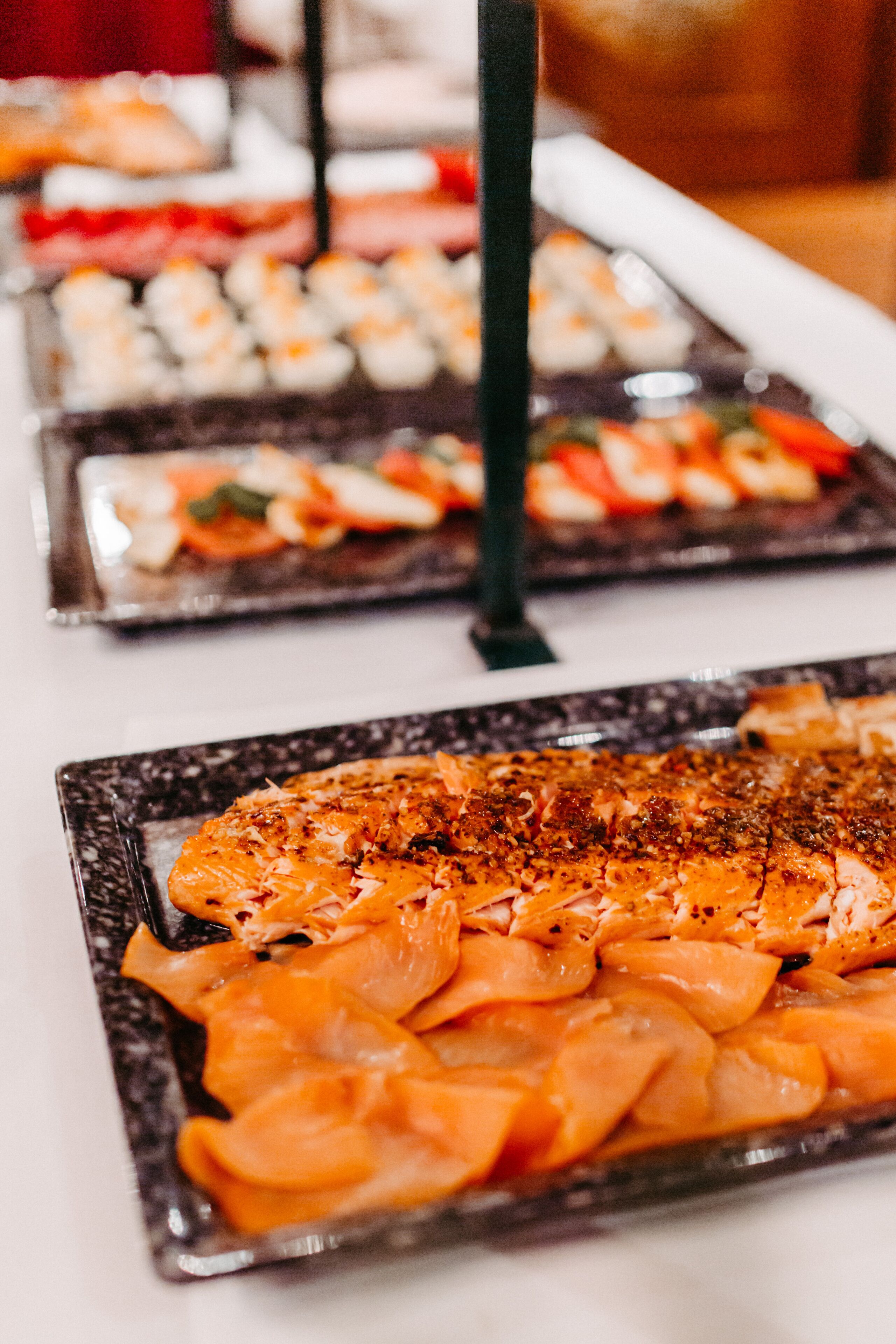A buffet with various dishes, including a salmon dish garnished with herbs.