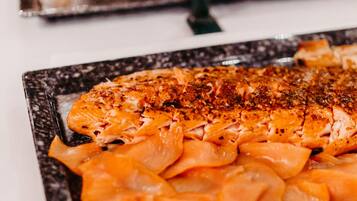 A buffet with various dishes, including a salmon dish garnished with herbs.