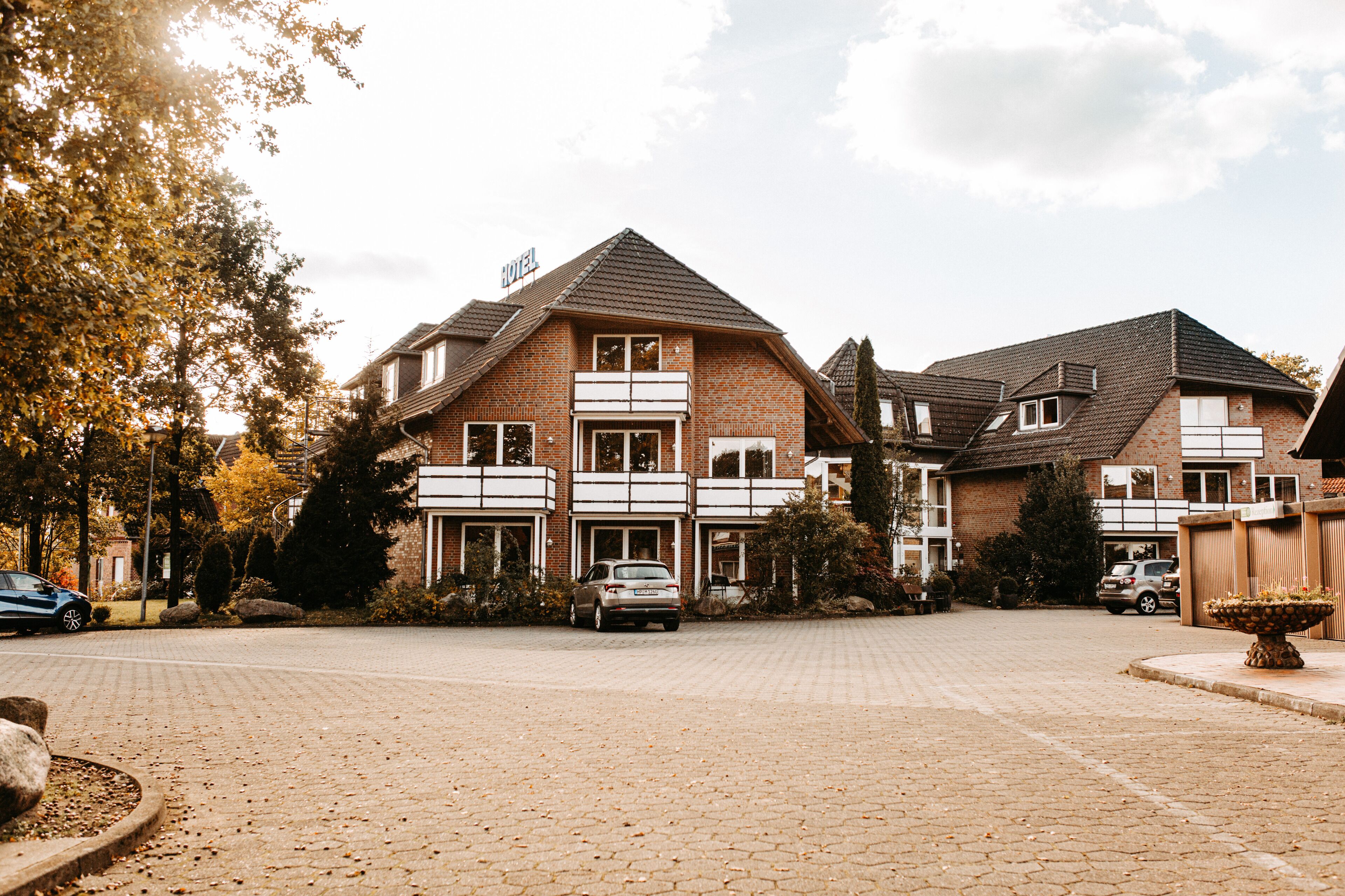 Un hôtel de deux étages avec une façade en briques, de nombreux balcons et une allée pavée.