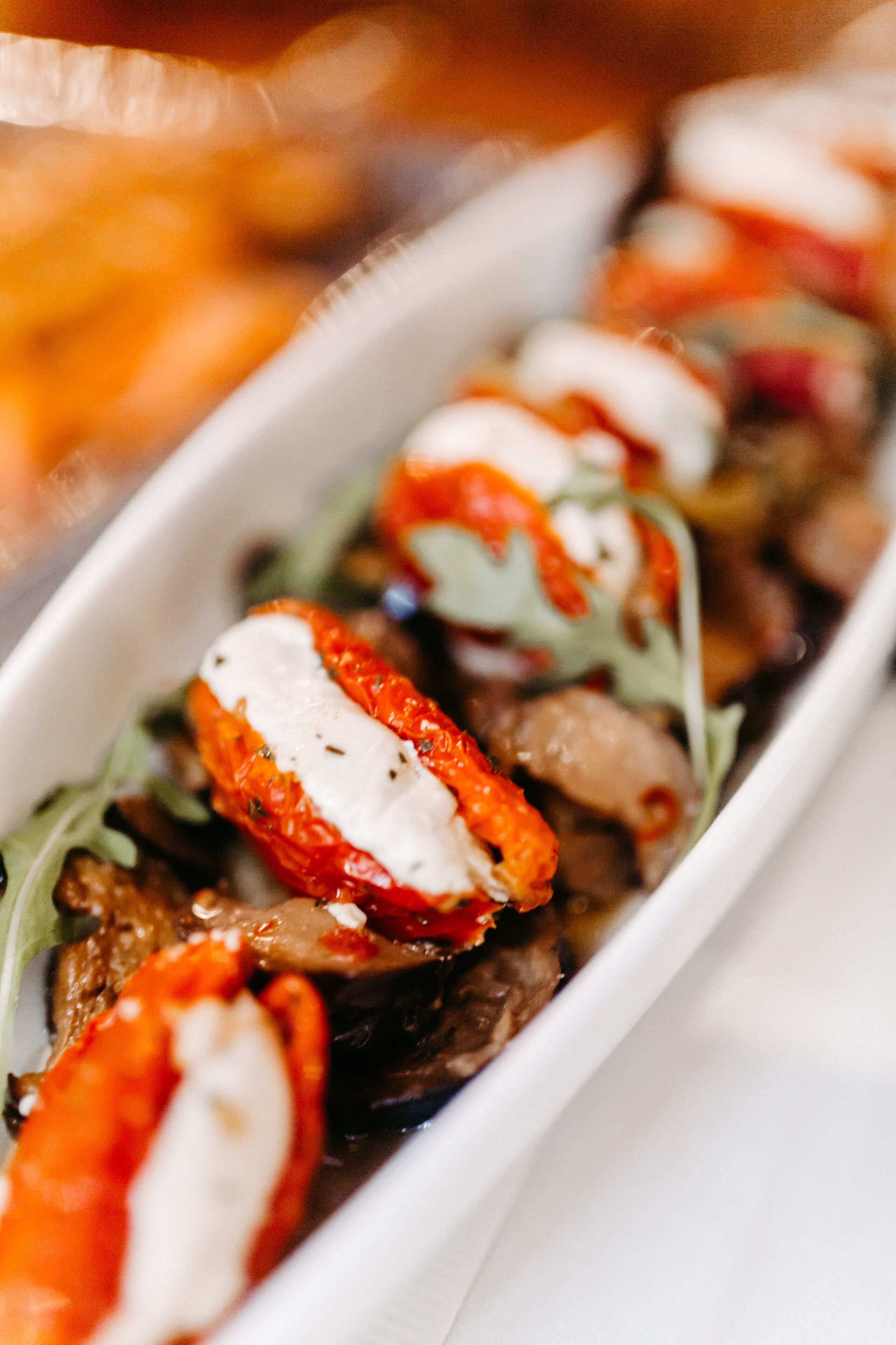 Primer plano de un plato con tomates cherry, mozzarella y hojas verdes.