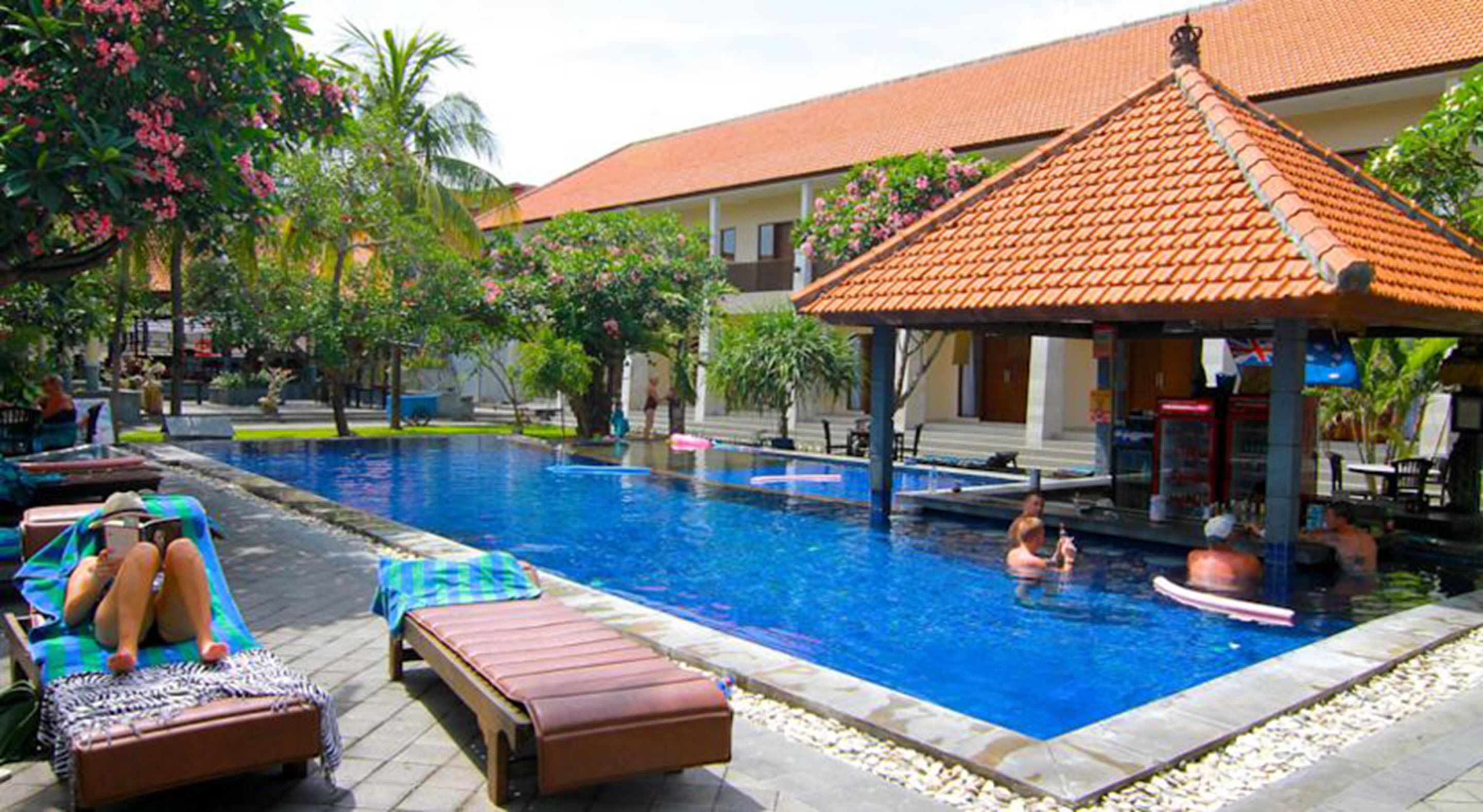 Uma área de piscina com espreguiçadeiras e um espaço coberto para sentar.
