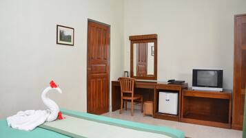 A hotel room with a bed, a desk with a chair, a television, and a small refrigerator.