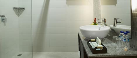 Un bany modern amb rajoles blanques, un lavabo gran, una dutxa i dos penjalls per tovalloles.