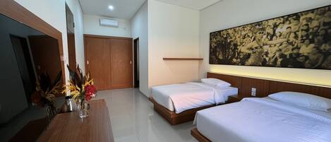 A hotel room with two beds, a wooden desk, a flat-screen TV, and a large wall painting.