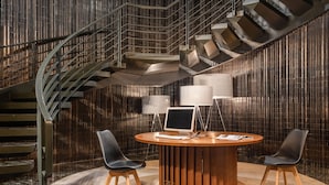 A modern interior with a spiral staircase, a round wooden table with two chairs, and a large screen. - Hotel Medium Valencia (Valencia)