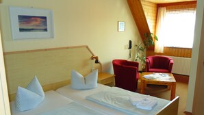 Een hotelkamer met twee bedden, een rode stoel, een houten tafel en uitzicht op het omliggende landschap.
