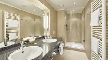 A modern bathroom with two sinks, a large mirror, and a glass-enclosed shower.