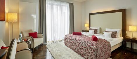 A hotel room with a large bed, a desk with a chair, a sofa, and a large mirror.