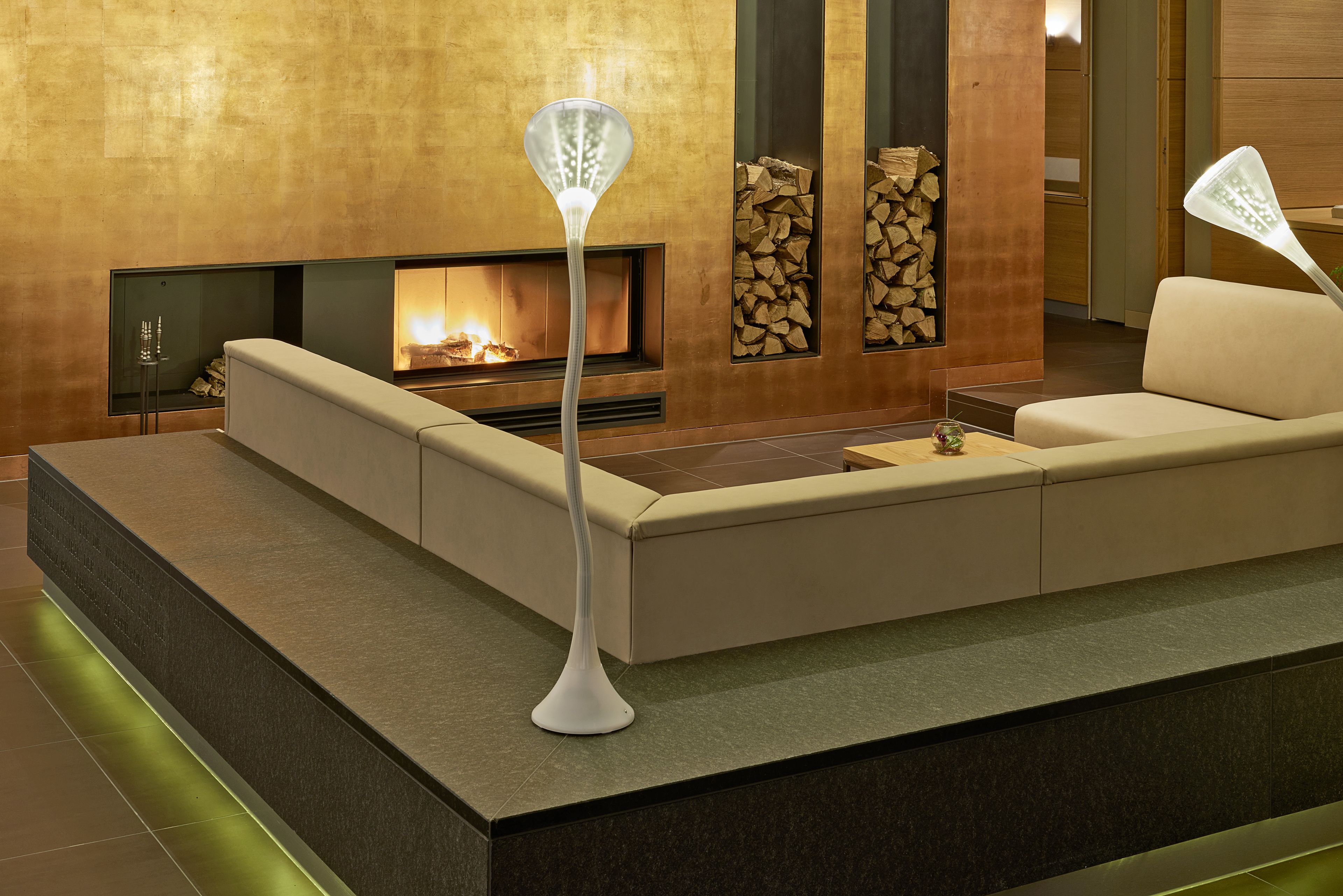 Un salon moderne avec un canapé, une cheminée et deux lampadaires.