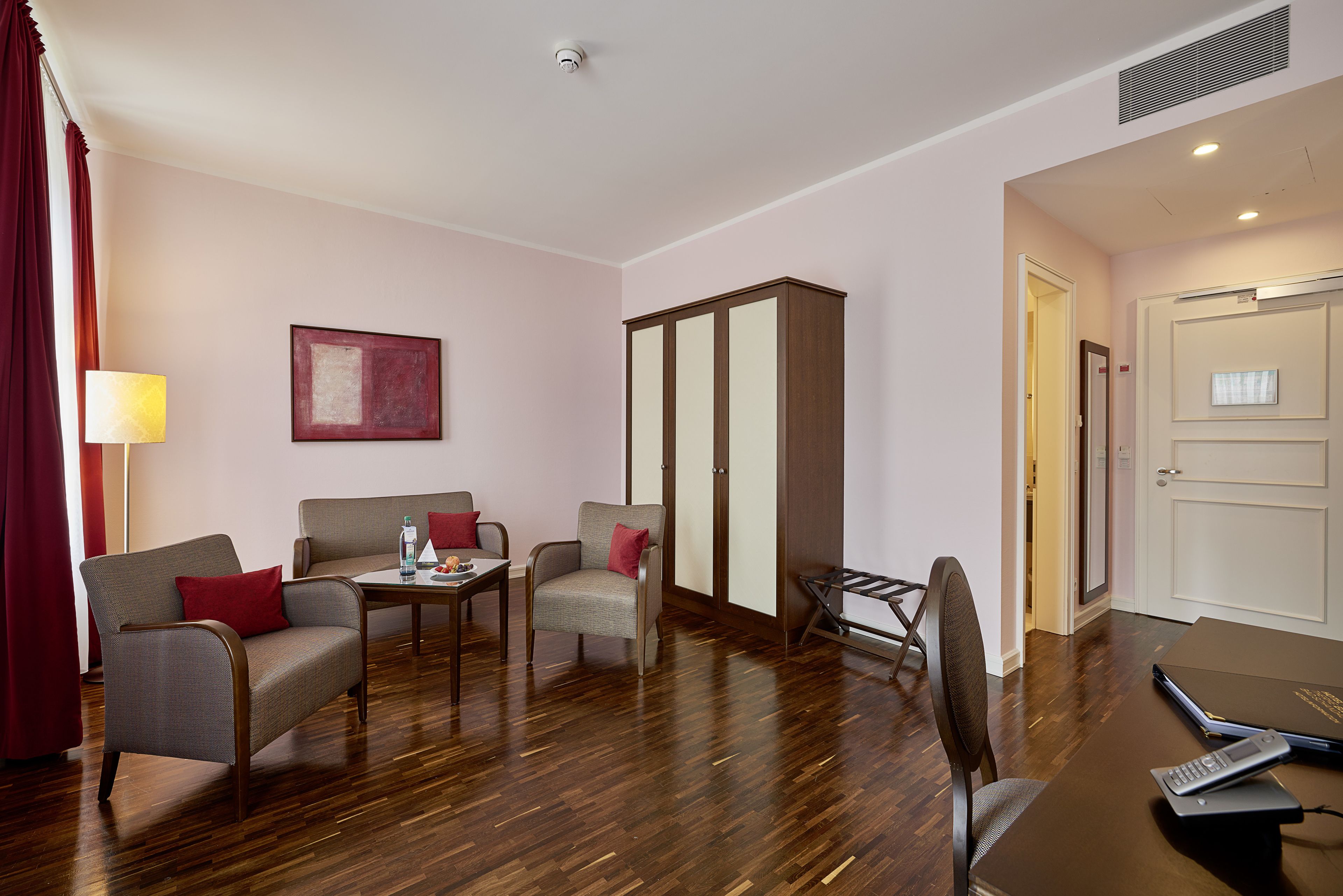 Habitación de hotel con sofá, sillas, una mesita, escritorio con una computadora portátil y armario.