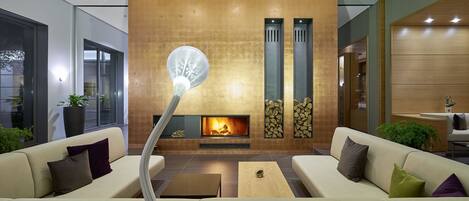 A modern living room with a fireplace, sofas, and a unique light fixture.