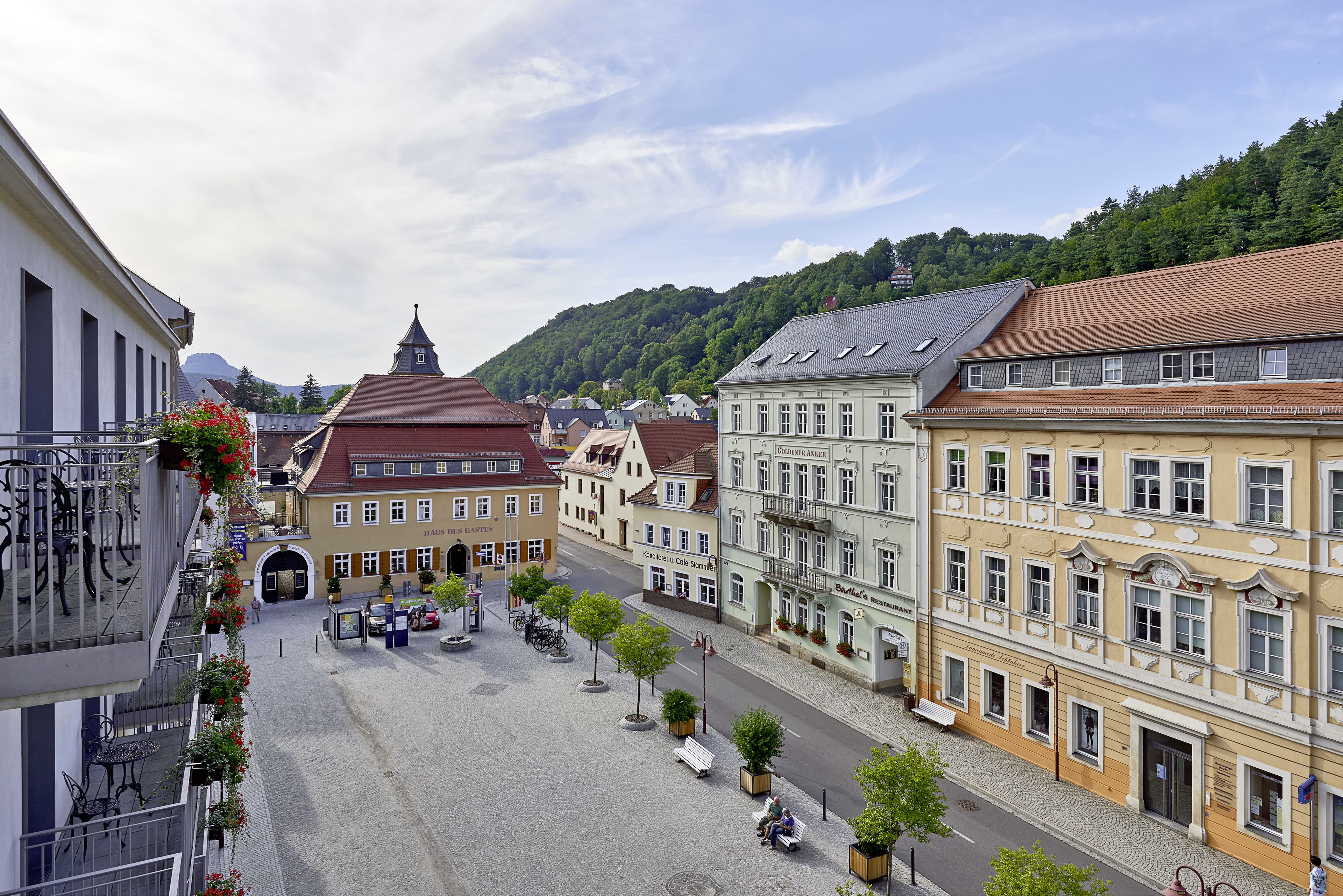 Eine Kopfsteinpflasterstraße mit historischen Gebäuden, einem Kirchturm und einem Café.