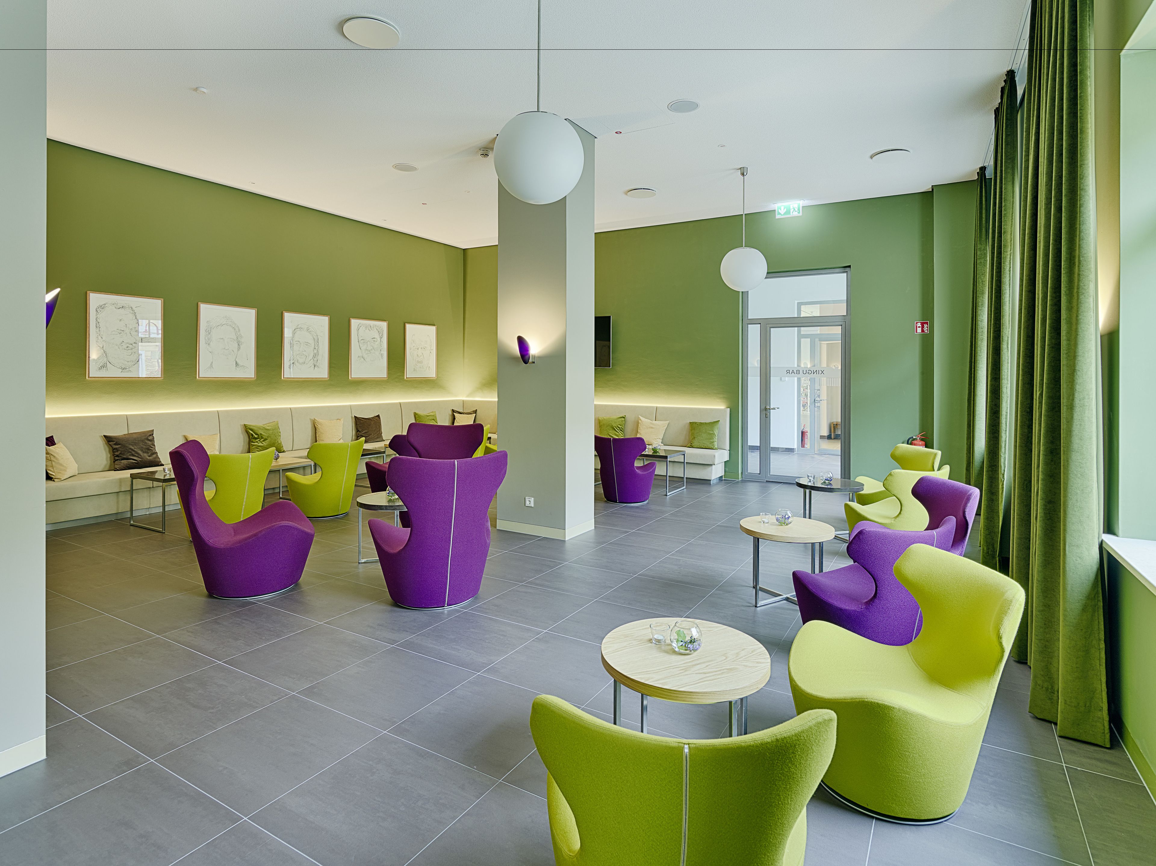 Een moderne lobby met groene wanden, paarse en gele stoelen en een receptiebalie.