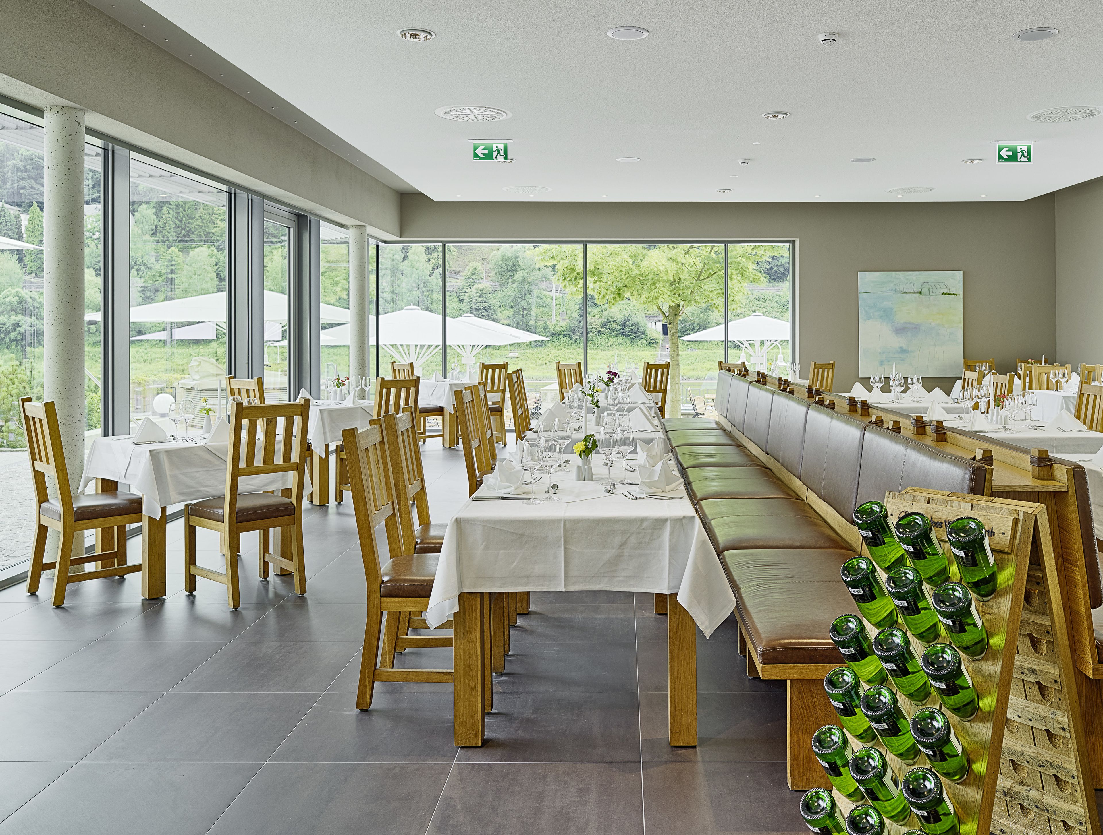 A restaurant with long tables, wooden chairs, and a wine rack.