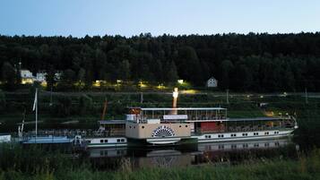 A riverboat with a dining area and a logo on the side.