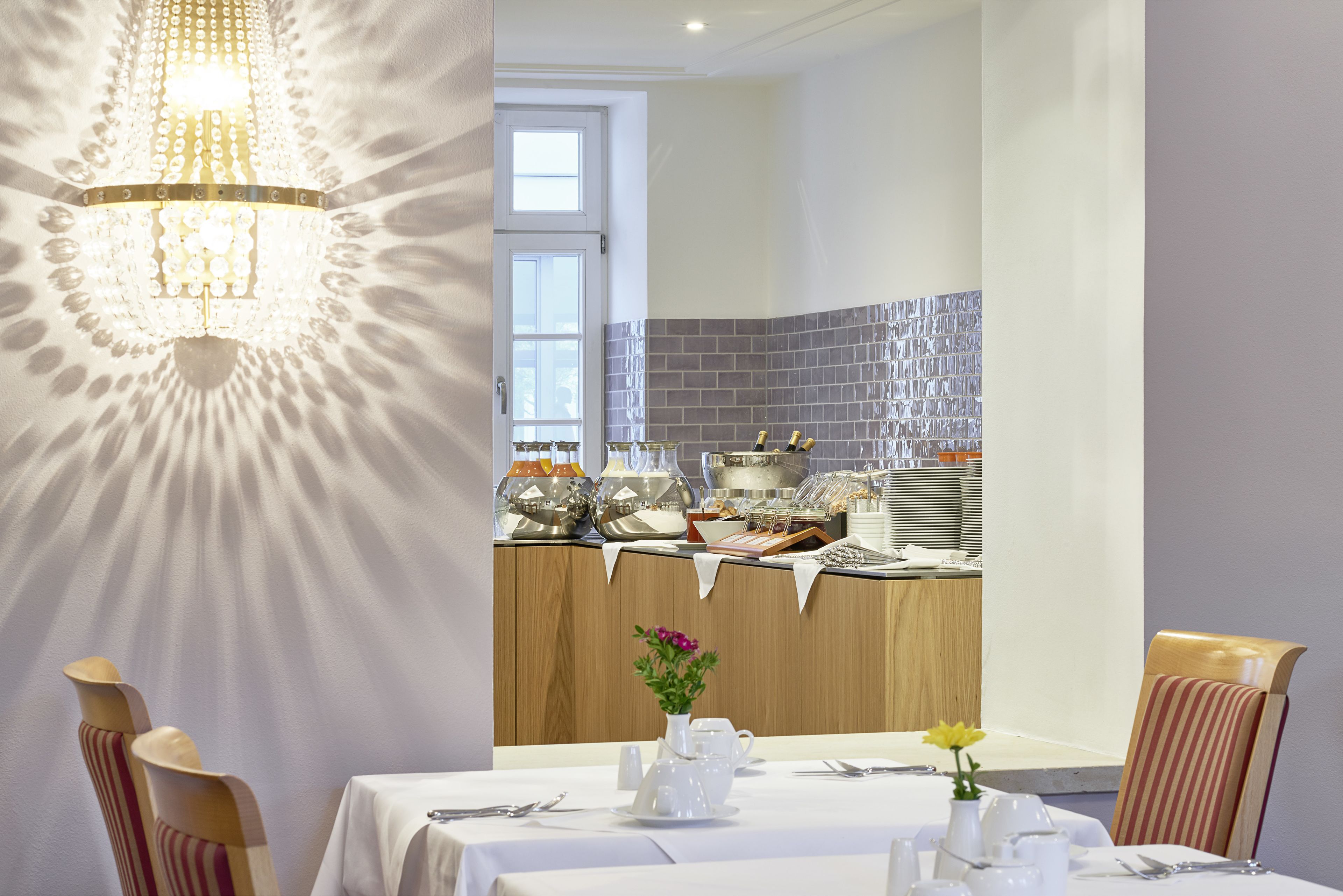 A dining area with a chandelier, a buffet counter, and a table set for two.