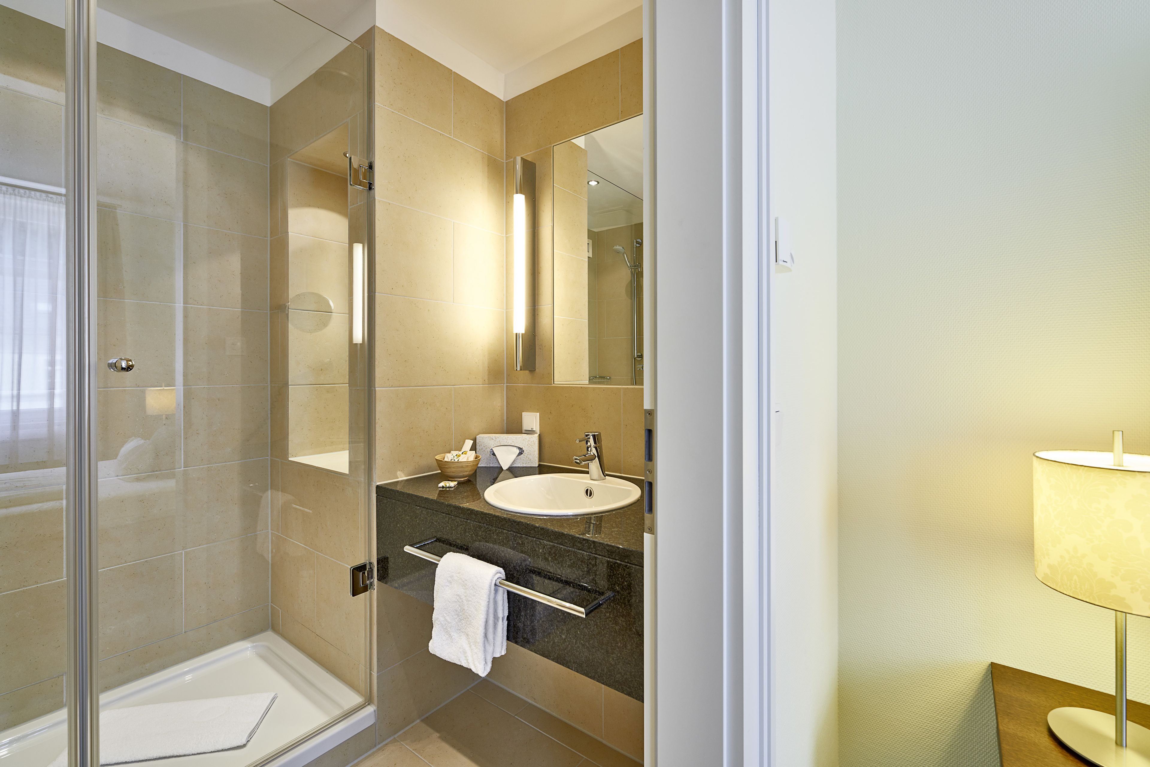 A modern bathroom with a glass-enclosed shower, a sink with a towel rack, and a mirror.