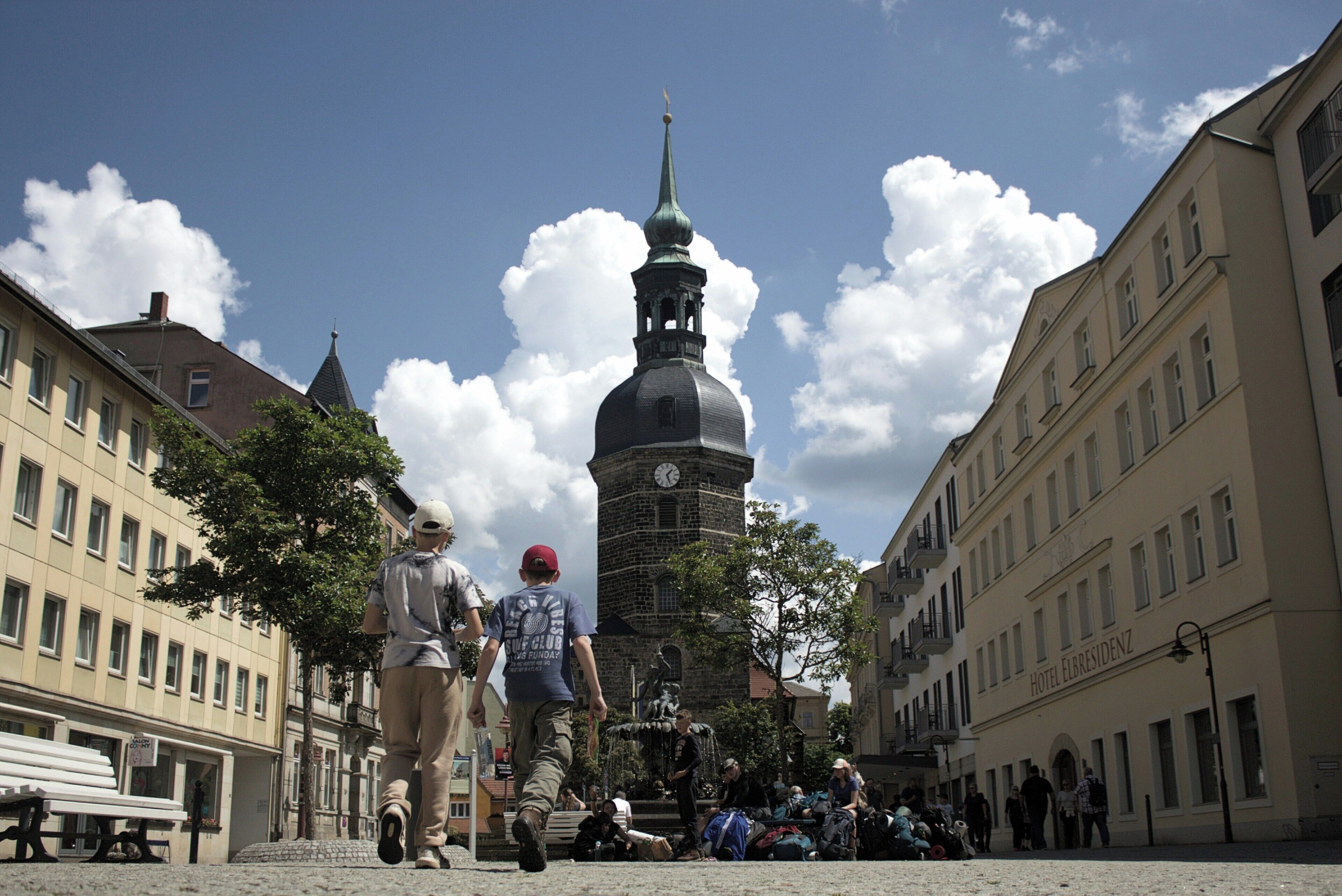 A historic building with a clock tower, a fountain, and a hotel named "Hotel Elisabethenz" in the background.