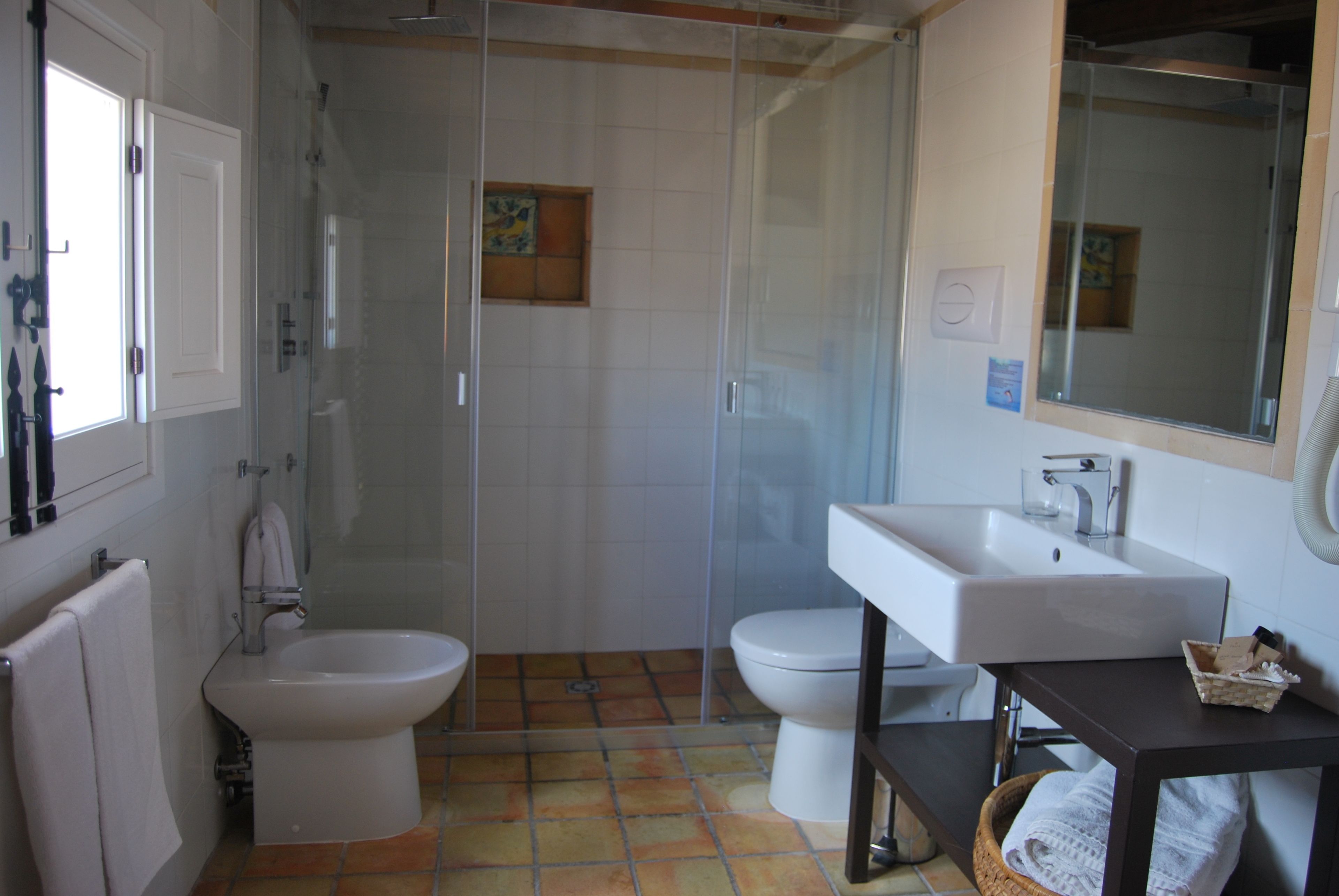 Un baño con ducha, inodoro, bidé, lavabo y espejo.