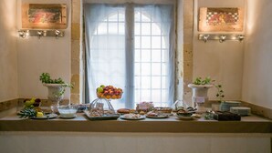 A breakfast buffet with various food items and a window with curtains. - Alla Giudecca (Syracuse)
