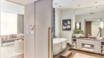 A modern bathroom with a freestanding bathtub, a large mirror, and a vanity with storage drawers.