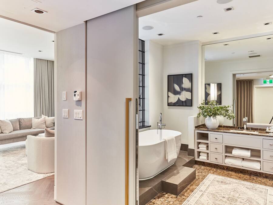 A modern bathroom with a freestanding bathtub, a large mirror, and a vanity with storage drawers.