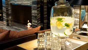 A clear glass pitcher filled with a beverage, garnished with lemon slices and mint leaves, placed on a tray with a candle and salt and pepper shakers.