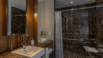 Ein modernes Badezimmer mit einem мраморный Waschbecken, einem großen Spiegel, einer Dusche mit Glastür und einem Handtuchhalter.