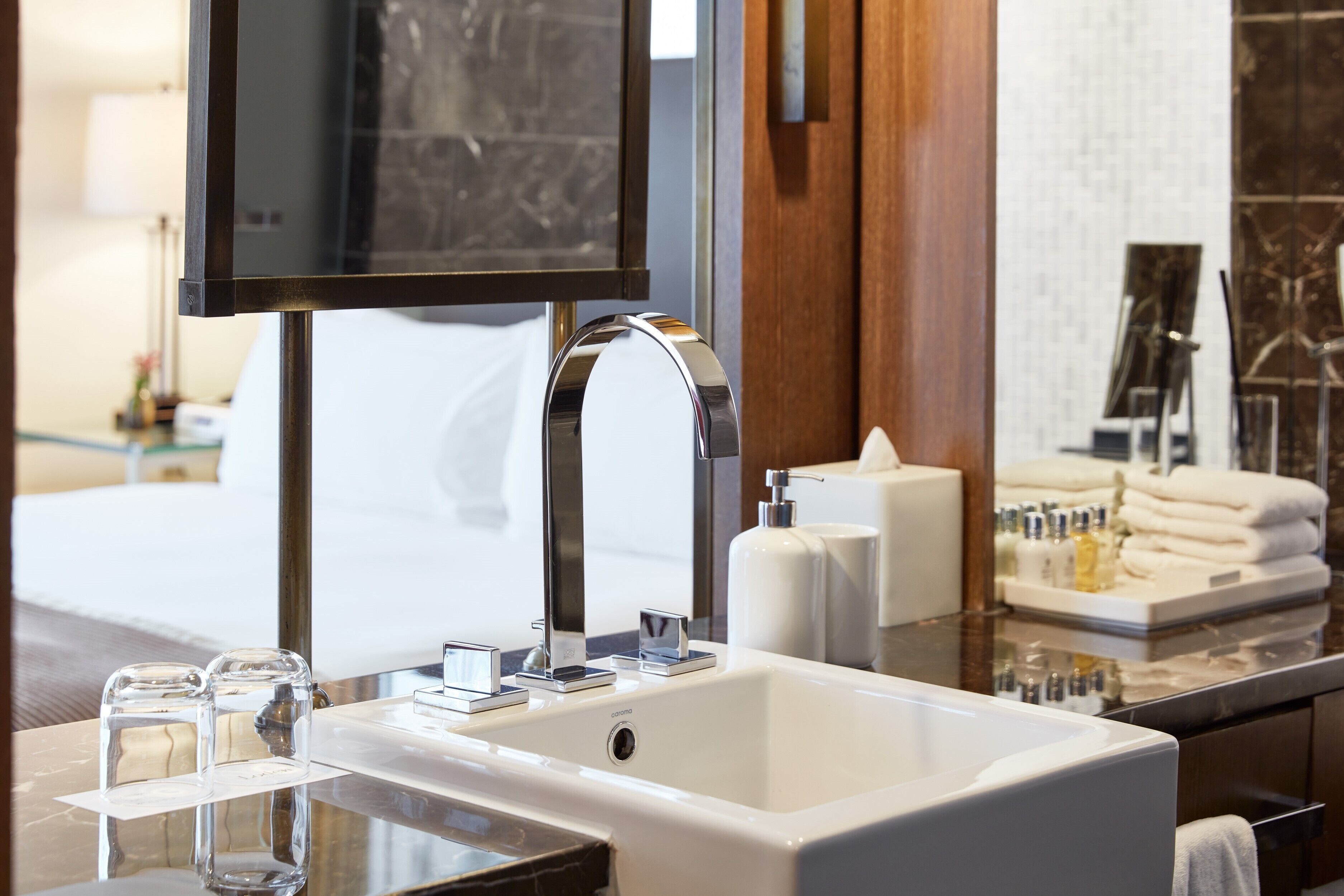 Un baño moderno con un espejo grande, un lavabo blanco y una encimera de mármol.