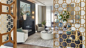 A modern living room with a fireplace, sofas, a coffee table, and a decorative partition. - Loden Hotel (Vancouver)
