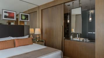 A hotel room with a large bed, bedside lamps, a mirror, and a wooden wardrobe.