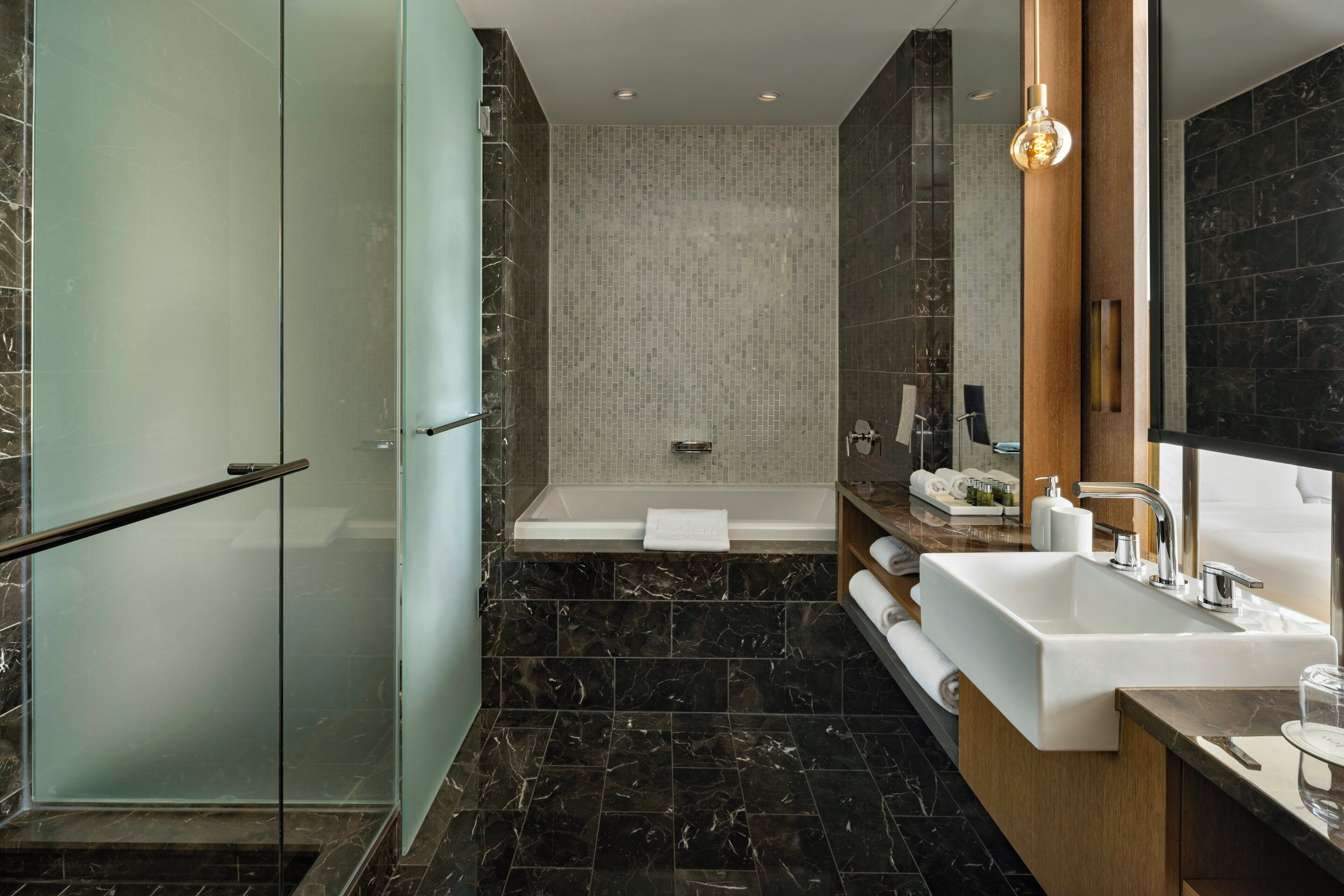 Ein modernes Badezimmer mit Duschkabine aus Glas, einer freistehenden Badewanne und einem Waschtisch mit großem Spiegel.