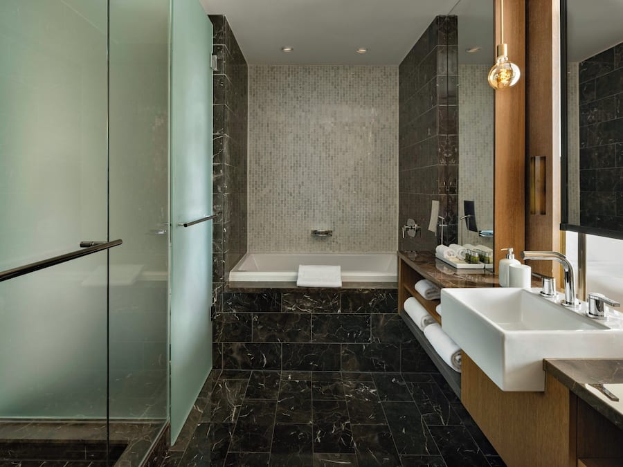 Ein modernes Badezimmer mit Duschkabine aus Glas, einer freistehenden Badewanne und einem Waschtisch mit großem Spiegel.