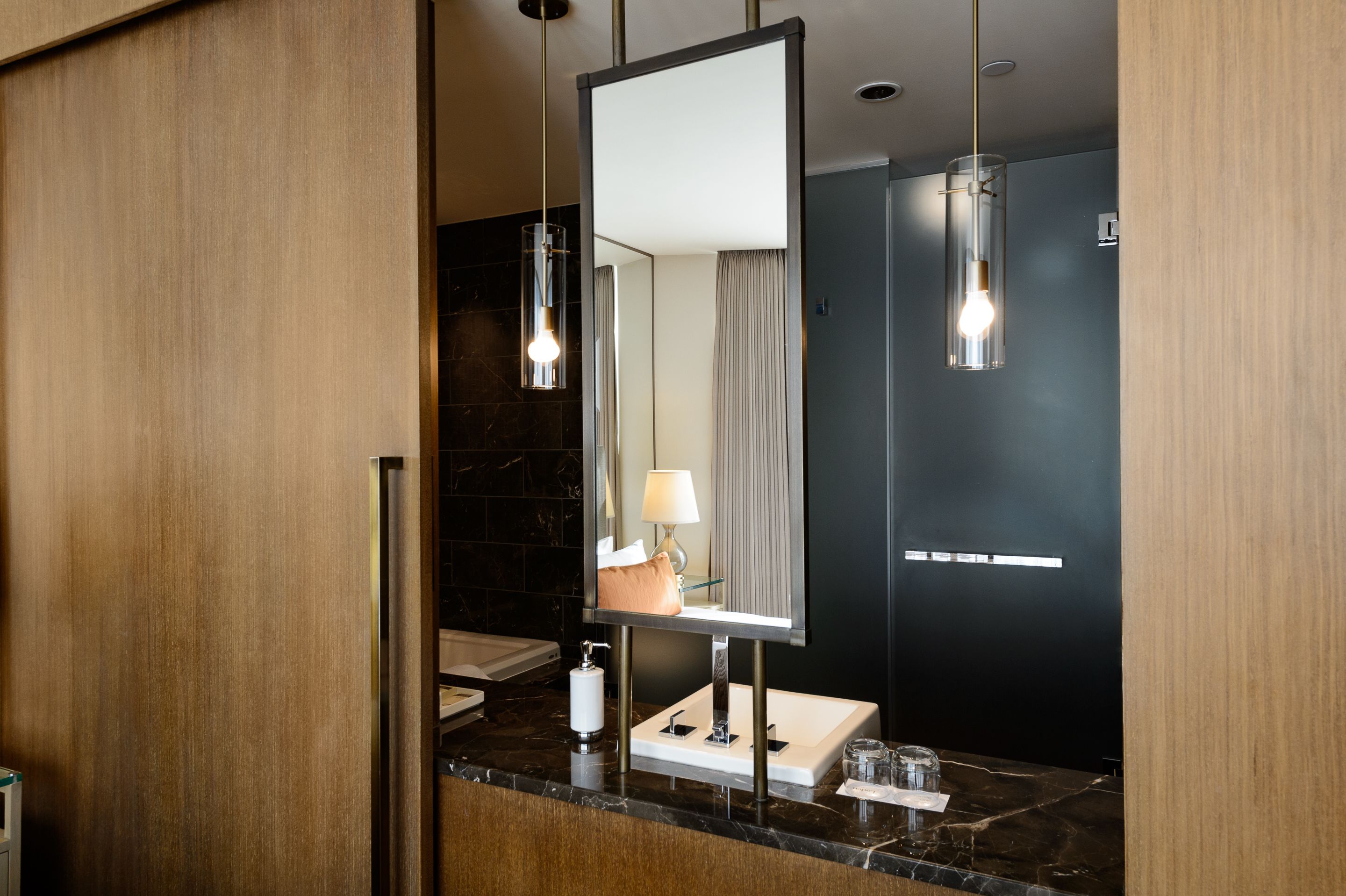 A modern bathroom with a large mirror, a sink, a towel rack, and a glass shower enclosure.