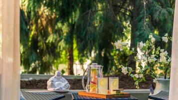 Un cadre extérieur paisible avec une table ornée d’une statue de Bouddha, d’une carafe de thé glacé et de verres.