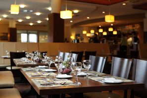 Un restaurante con mesas largas preparadas para comer, con cristalería transparente y menús.