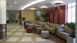 A modern lobby with a checkered floor, leather sofas, and a staircase in the background.