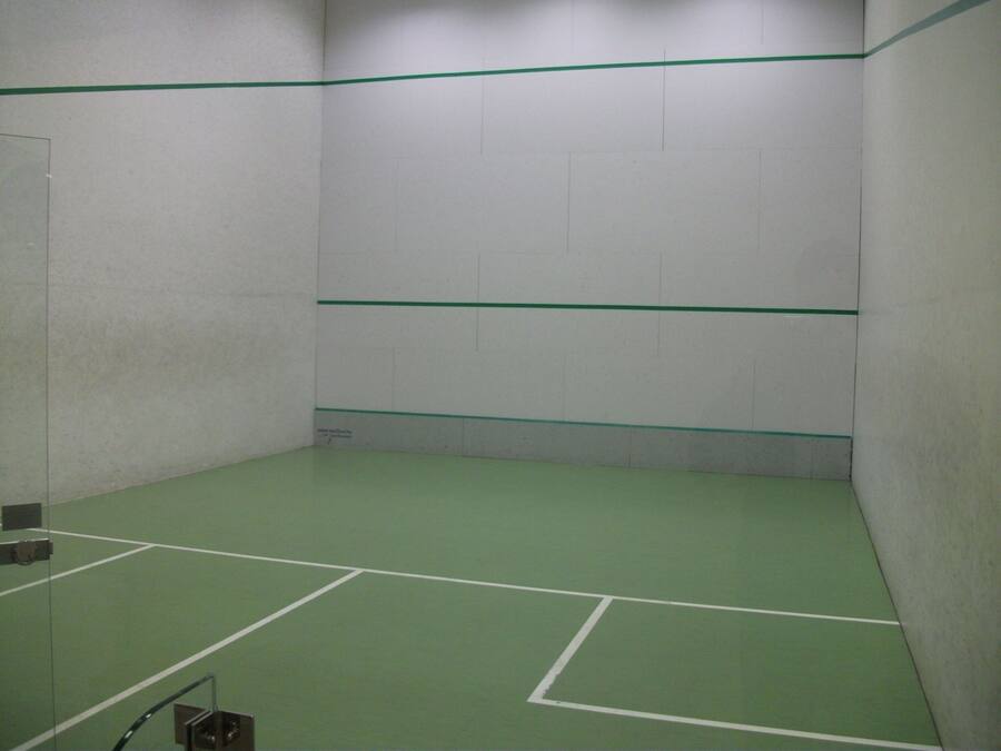 A squash court with green flooring and white walls.
