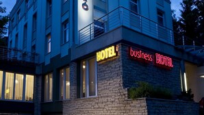 Un hôtel à plusieurs étages, reconnaissable à son grand panneau indiquant « HÔTEL » et à un autre panneau précisant « HÔTEL D’AFFAIRES ».