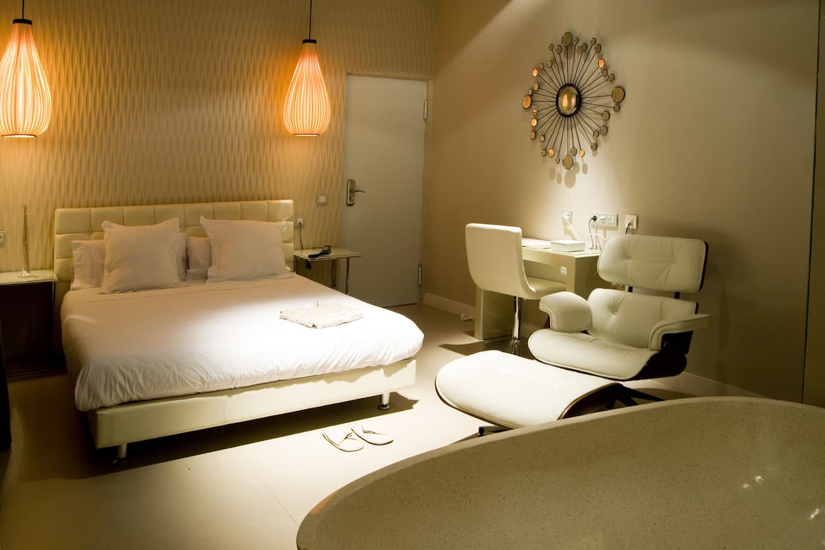 Une chambre d’hôtel moderne équipée d’un grand lit, d’un bureau, d’une chaise et d’une baignoire.