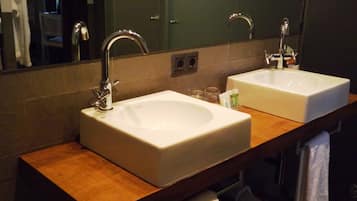 A bathroom with two white sinks, a wooden countertop, a mirror, and a towel rack.