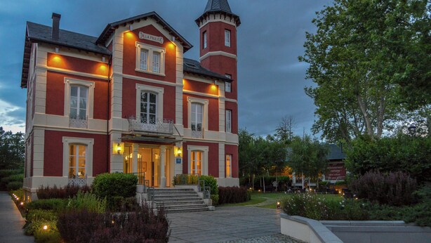 A large, red brick building with a tower and a balcony.