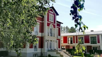 Um edifício vermelho e branco com uma escadaria central e um jardim bem cuidado.