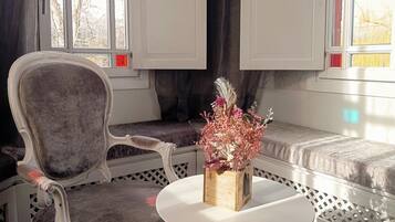 A seating area with a cushioned chair, a small round table, and a wooden vase with dried flowers.